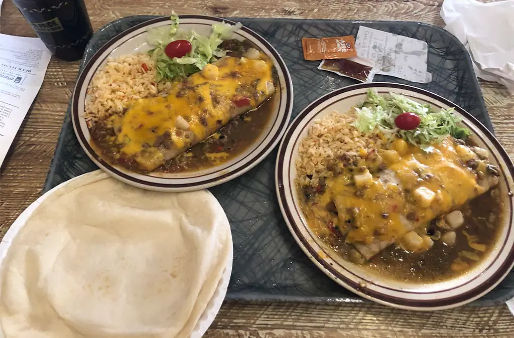 Photo of two plates with green Chile smothered burritos at the Frontier Albuquerque with tortillas and honey on the side
