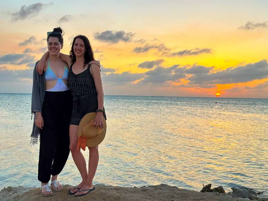 Photo of two women posing on the beach with the ocean behind them for sunset at Secret Beach on Ambergris Caye in Belize.
