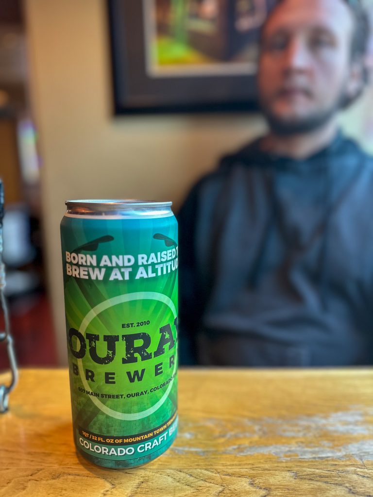 Photo of a Ouray Brewery 15 oz. Growler in a teal can with bright green logos.