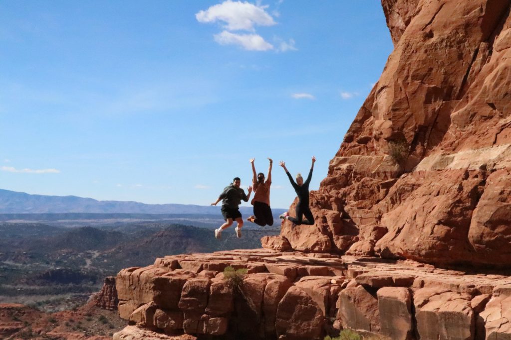 Stephanie and Friends jumping for a photo opportunity at the top of Cathedral Rock trail in Sedona for Applied Worldwide blog "Feeling the Energy: Hiking Cathedral Rock Vortex in Sedona"