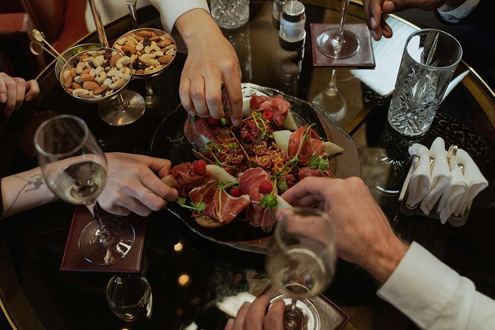 Photo of a group eating at a restaurant showing their hands reaching for a shared plate for Applied Worldwide Lifestyle blog "Top Secret Ingredients for Running a Profitable Restaurant"