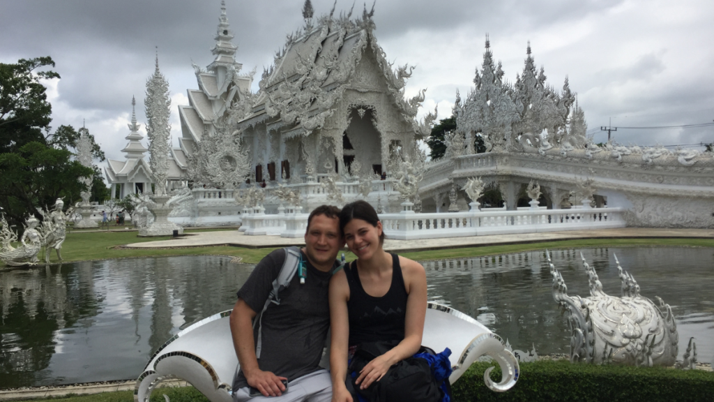 Photo of Stephanie an dLuke sitting out front to the White Temple in Chiang Rai Thailand for Applied Worldwide blog Why Thailand Is One of the Most Romantic Places to Propose
