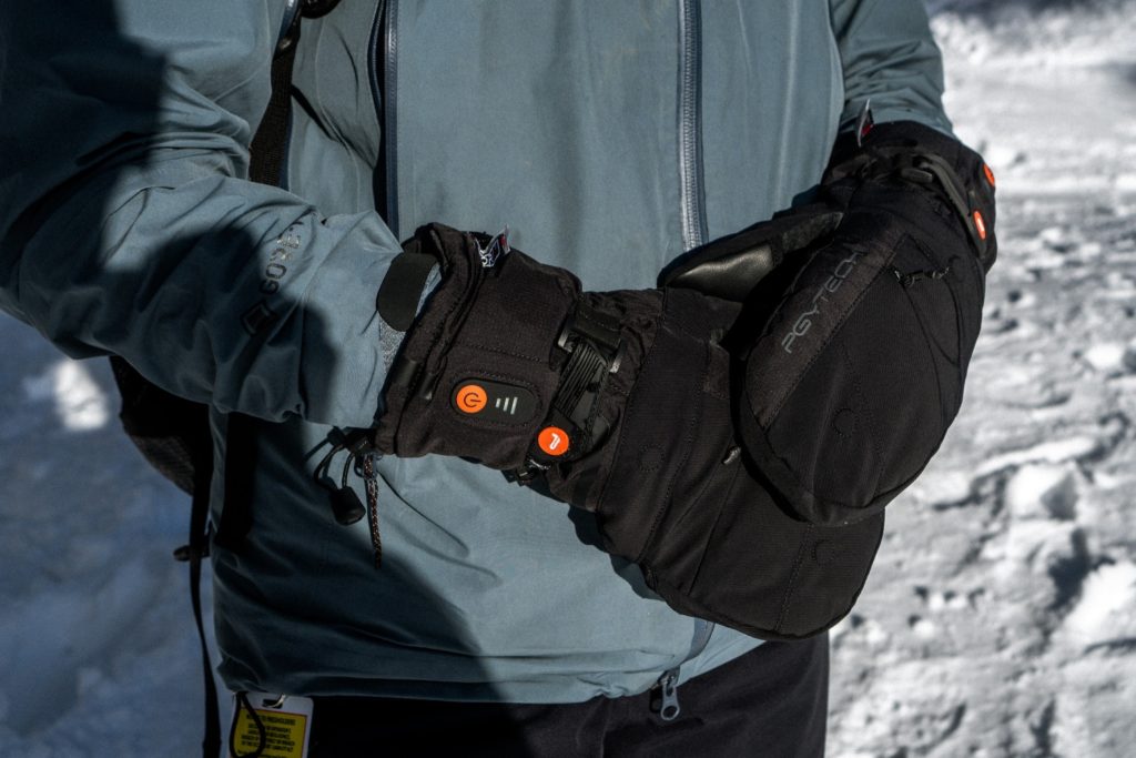 Person wearing black heated ski mittens in snow for Applied Worldwide blog "Travel Smart: Essential Gear for Cold Weather Journeys"