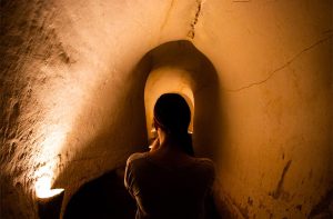 Photo of a woman from behind as she is walking into a tunnel carved from natural rock to exit the Caverns of Sonora.