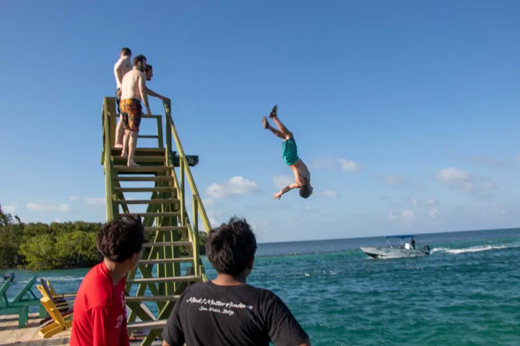 Man in the air mid-backflip after jumping off the diving board at the Lazy Lizard bar and grill in Caye Caulker.