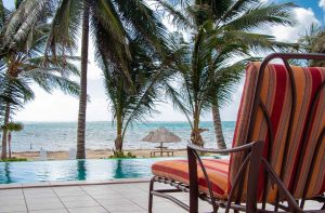 Photo of lounge chair next to beach front pool with palm trees and the Caribbean Sea in the background for blog on Experiential Travel and the Essence of Authentic Exploration
