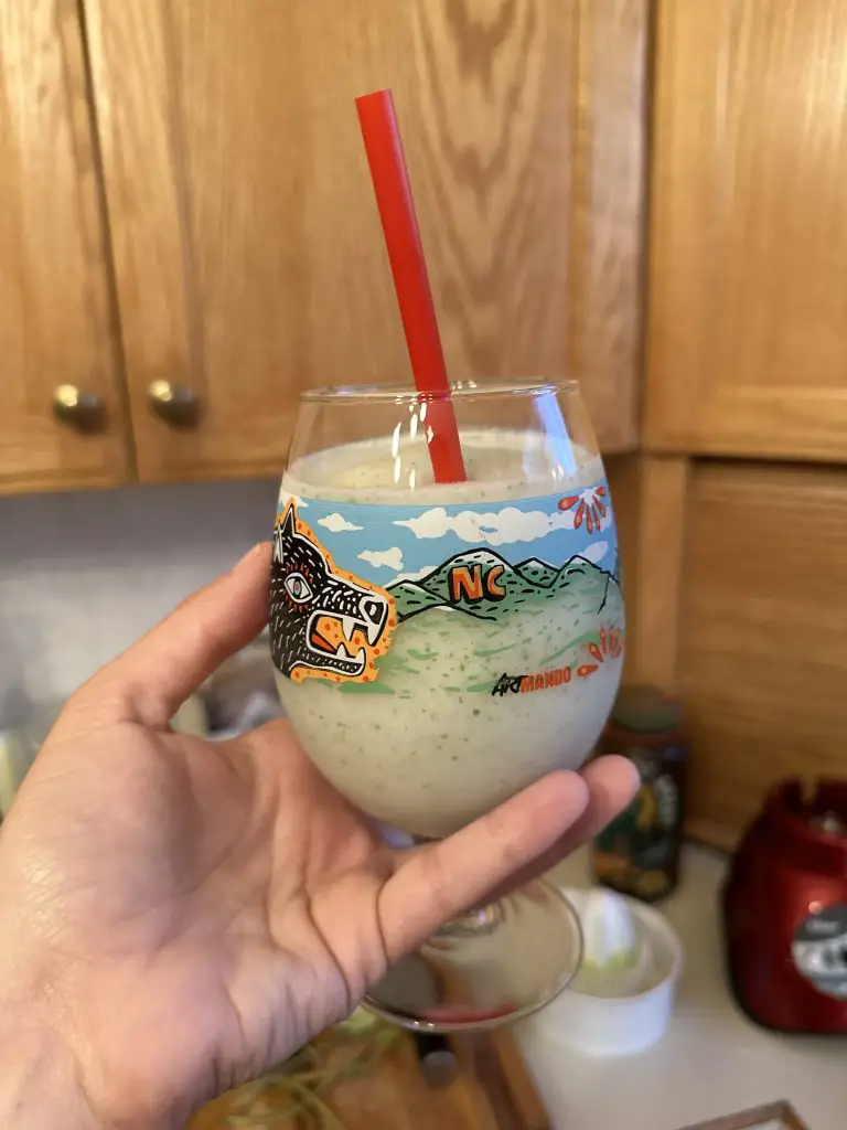 Photo of Stephanie holding her homemade coconut mojito served in a limited edition new Belgium brewery beer glass with original artwork by Armando Silva.