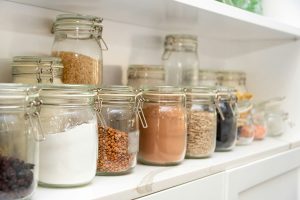 Photo of jars with whole food ingredients on a shelf for Applied Worldwide Lifestyle blog "A Quick Guide to Building a Healthy Pantry"