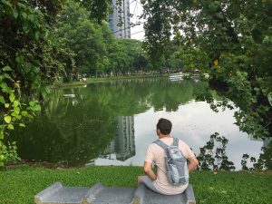 Photo of Luke sitting in a park in Bangkok, Thailand for Applied Worldwide Lifestyle Blog titled "Preparing for Your Upcoming Summer Vacation: 4 Key Things to Consider"