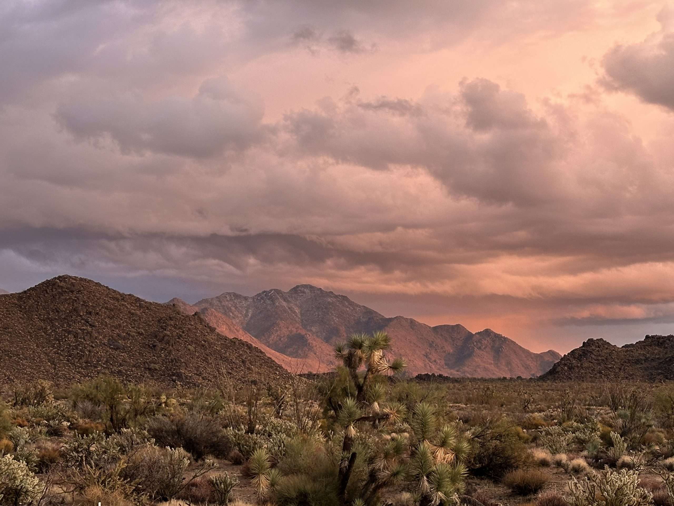Photo of Arizona's Hualapai Mountains lit up under a story sunset for Applied Worldwide blog on How I Built Community while Living Off the Grid