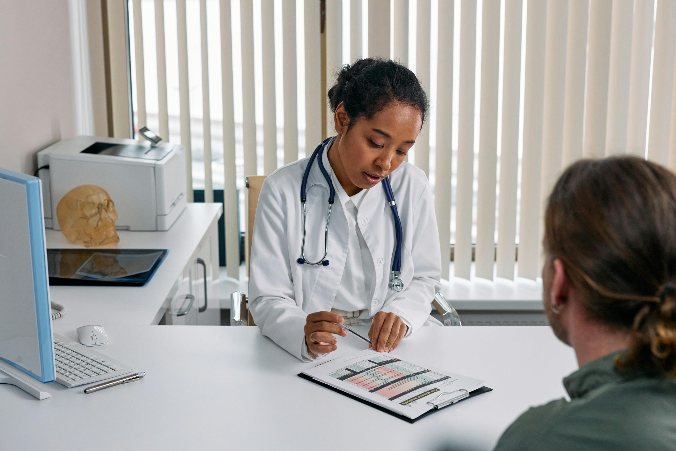Photo of female doctor sitting across a dest from a patient with forms for Applied Worldwide blog "How to Make Sure Your Healthcare Business Caters to Patients in a Digital World"