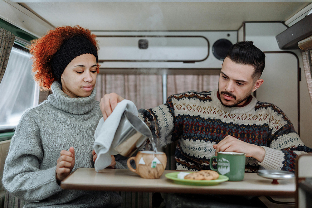 Photo of a couple eating breakfast in a camper van for Applied Worldwide blog "Your Road Trip Food Budget: How Much Are You Really Going To Need?"