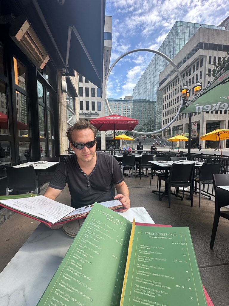 Photo of Luke sitting in a courtyard of a restaurant in downtown Montreal for Applied Worldwide blog "5 Types of Family Vacation Everyone Should Love"