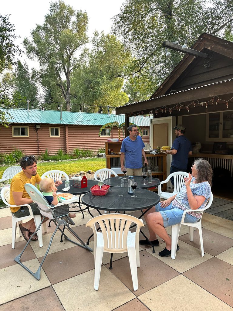 Photo of Stephanie's family sitting down for a BBQ dinner at Island Acres Resort in Gunnison, CO for Applied Worldwide blog "5 Types of Family Vacation Everyone Should Love"