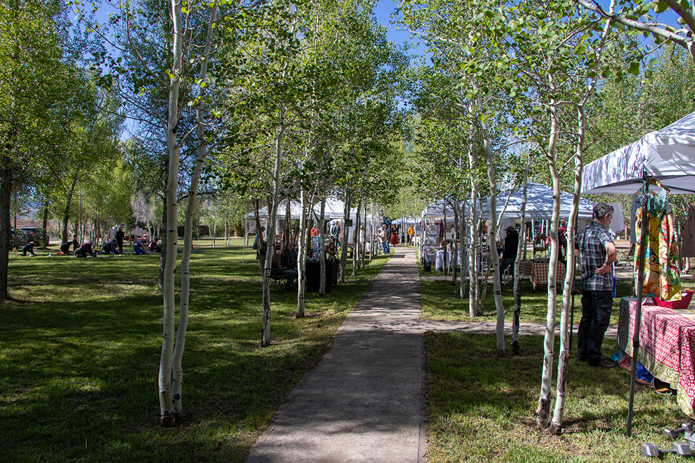 Photo of vendor booths lining a pathway framed by aspen trees for Applied Worldwide blog "Hartman Castle Welcome Community for First Time in Century"