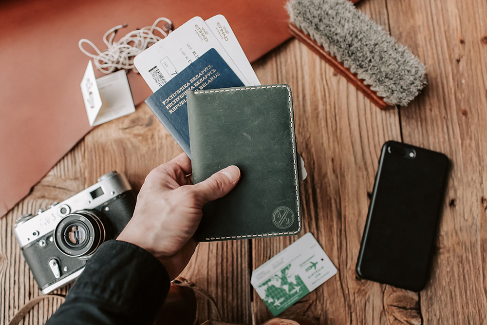 Photo of a man's hand holding passport and travel documents for Applied Worldwide lifestyle blog "Small Changes That Make Traveling So Much Easier"