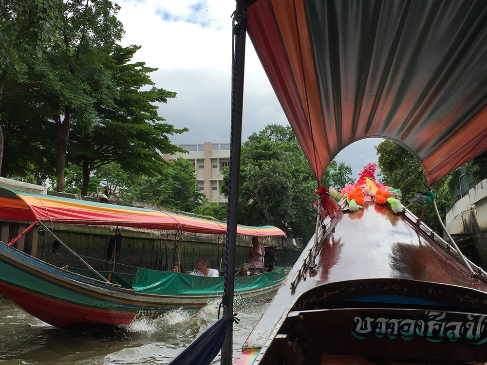 Photo of a boat on the river in Bangkok with flowers on the front bow for Applied Worldwide blog "4 Practical Tips to Plan a Vacation in Thailand Without the Stress"