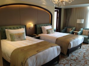 This photo shows a luxurious hotel room with two plush twin beds. The neutral color palette and elegant decor create a comfortable atmosphere. Soft lighting and tasteful furnishings enhance the sense of relaxation. The bedding and headboards appear inviting and well-coordinated. It’s an ideal space for travelers seeking rest and refinement.