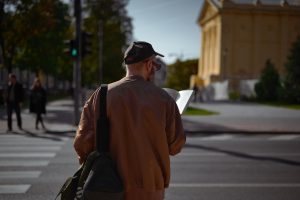 Photo of a man in a sunlit street looking at a travel guide taken from behind him for Applied Worldwide blog "Travel Hacking for a Better Quality of Life"