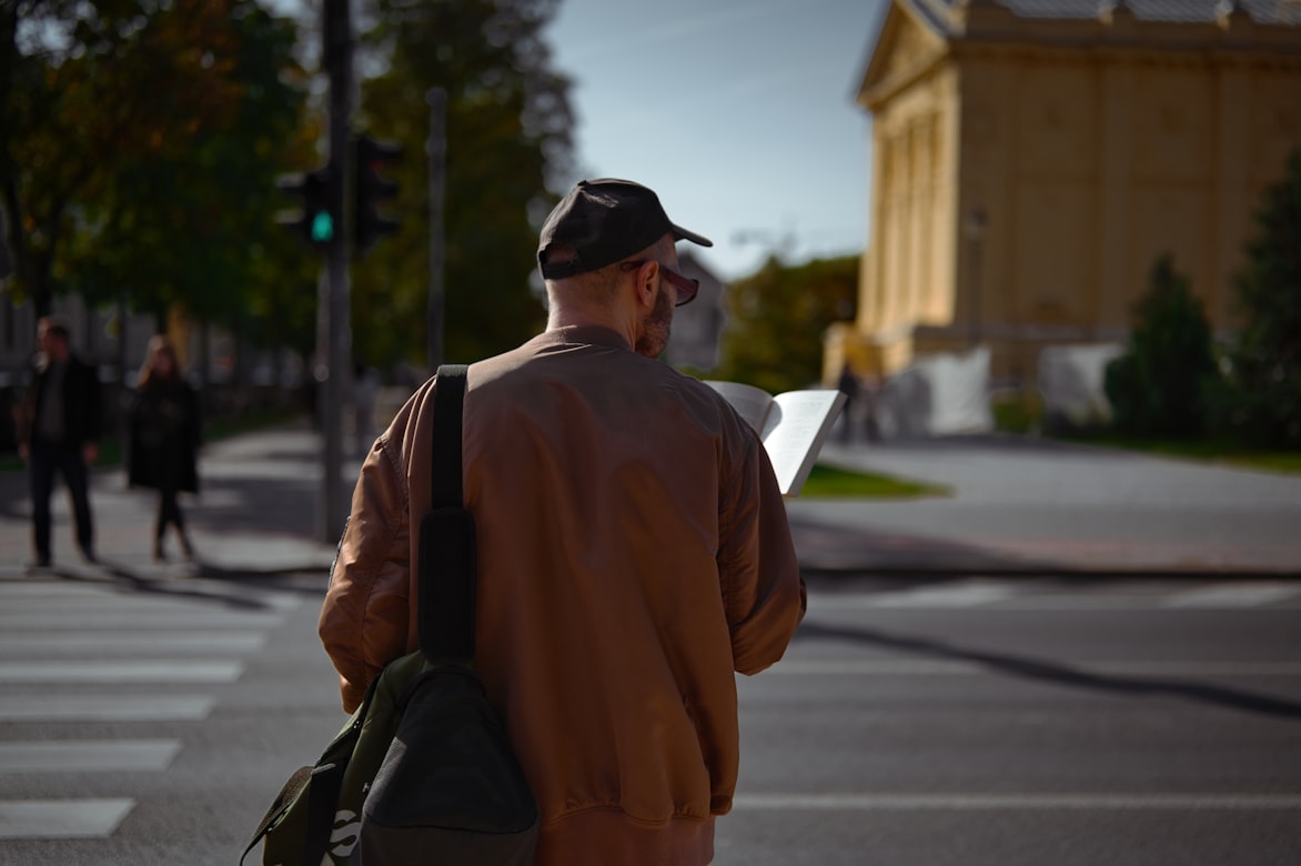 Photo of a man in a sunlit street looking at a travel guide taken from behind him for Applied Worldwide blog "Travel Hacking for a Better Quality of Life"